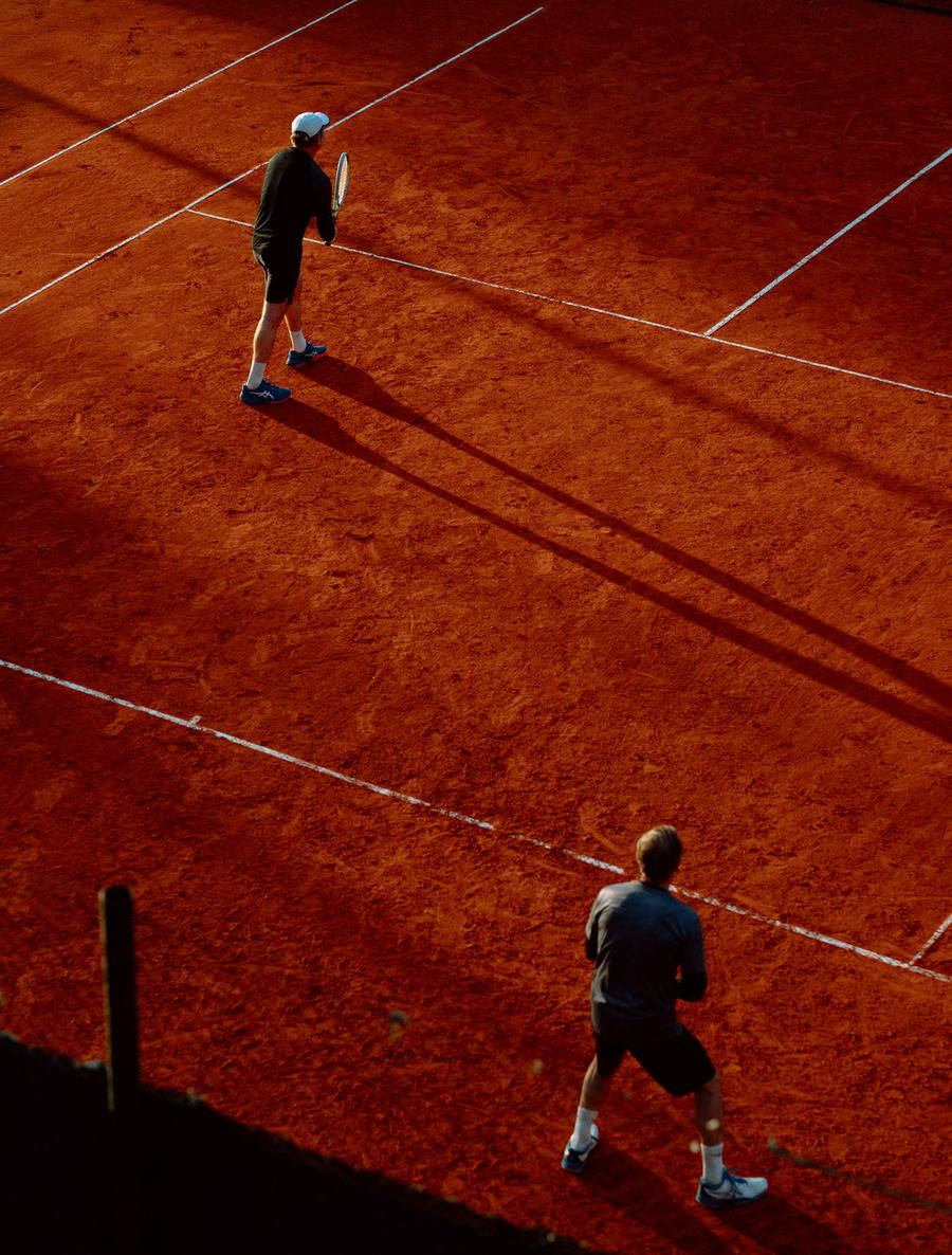 Two players crossing a clay court in late light
