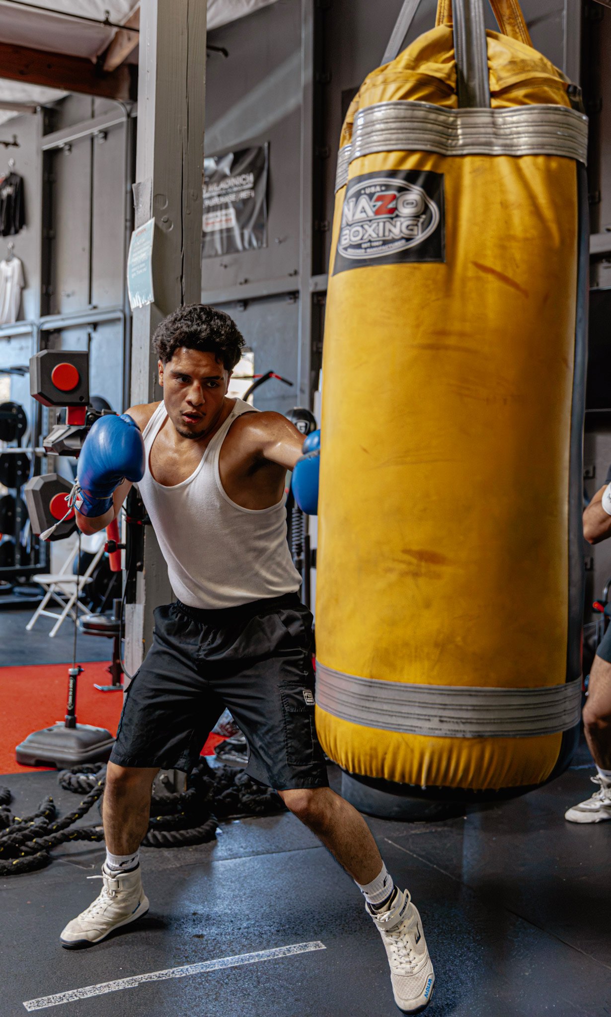 Juan Hernandez driving a right hand into a heavy bag in blue gloves