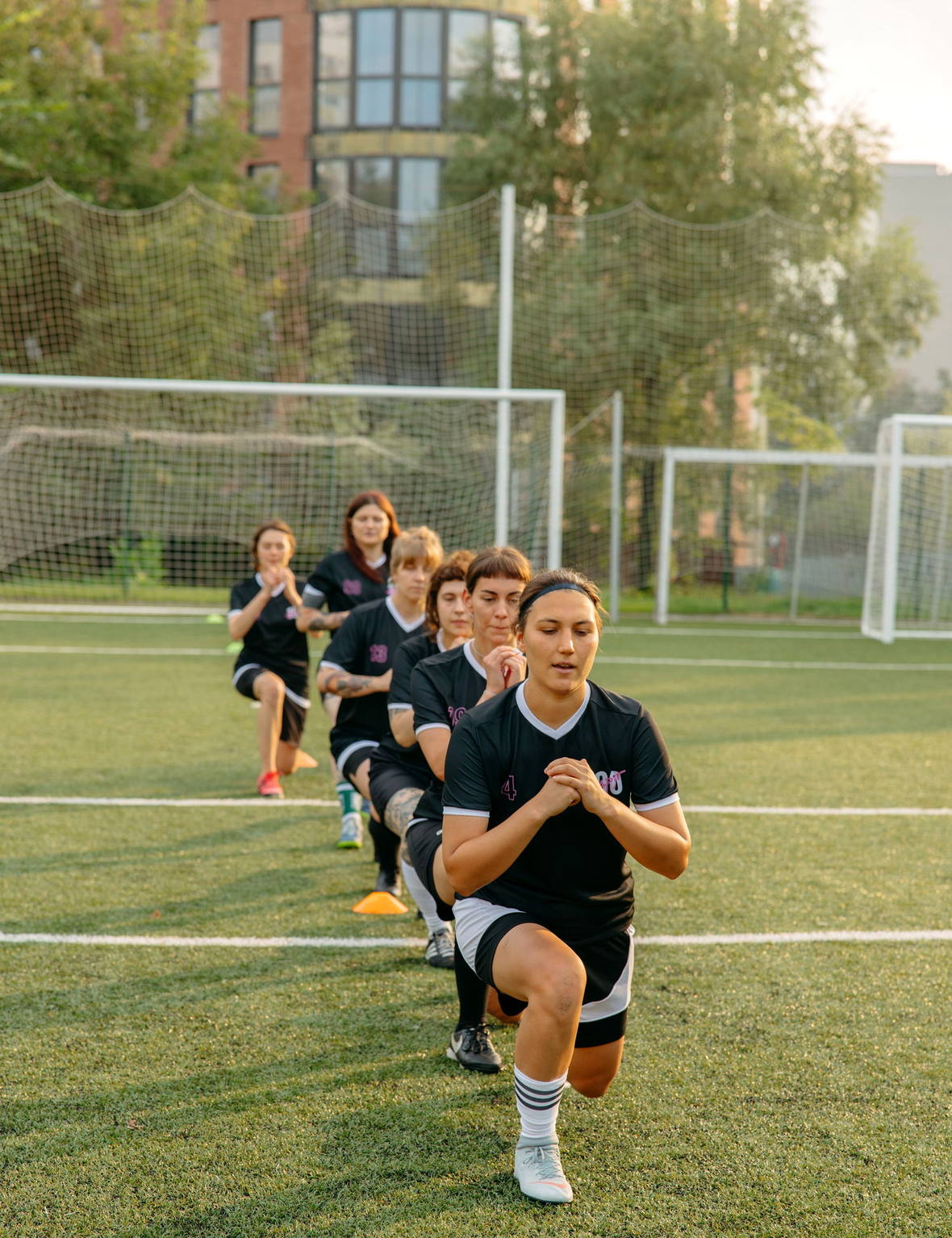 Athletes running through a training session on a floodlit pitch