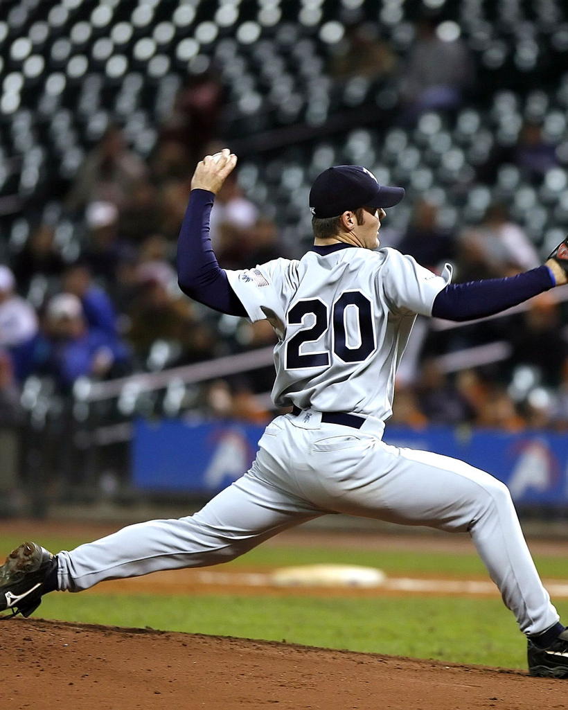 A pitcher at the top of his delivery under stadium lights